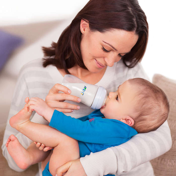 Bayi sedang minum susu formula menggunakan botol susu.
