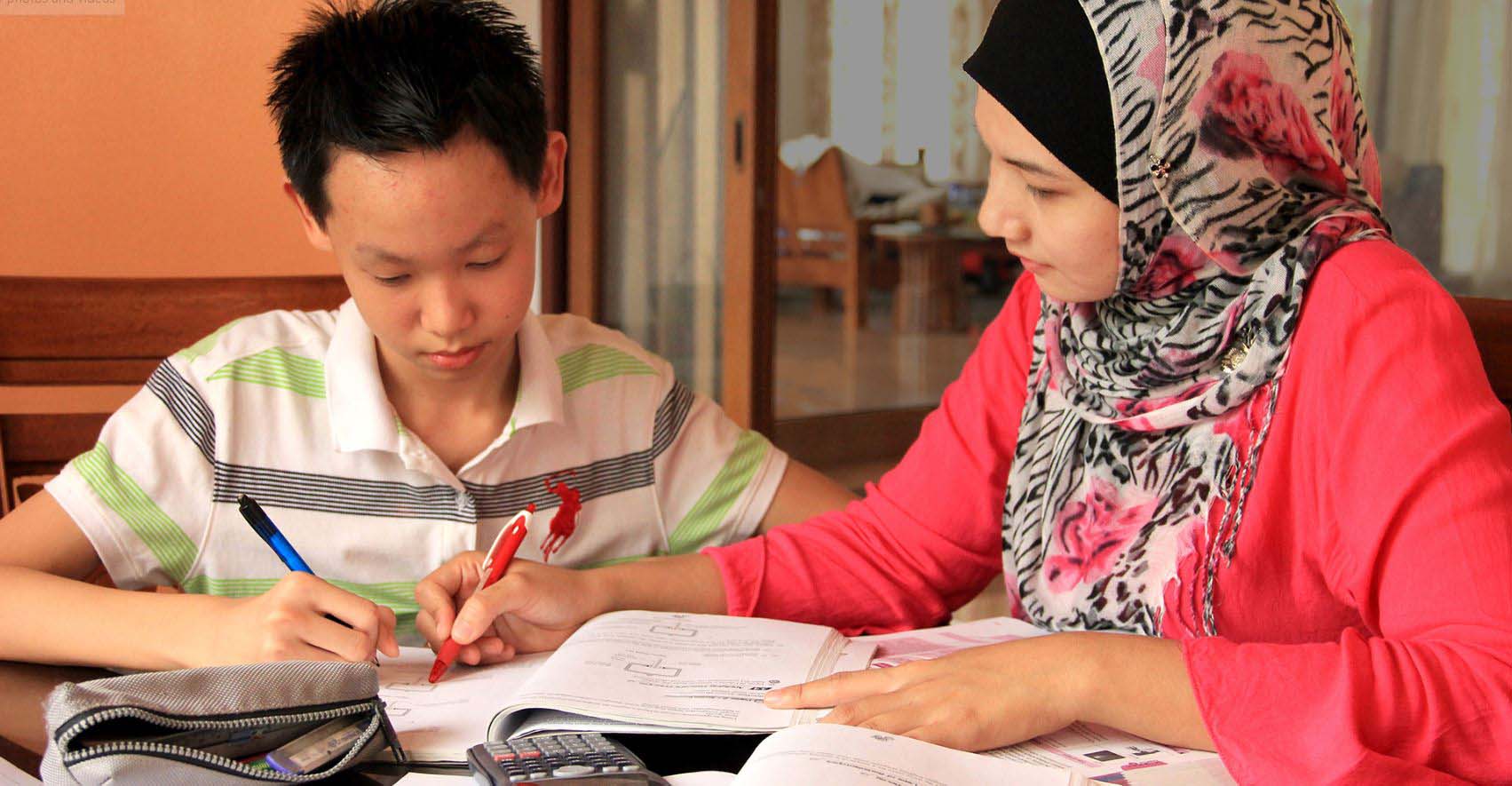 Ibu sedang bekerja menggunakan komputer riba di rumah untuk menambah pendapatan keluarga.