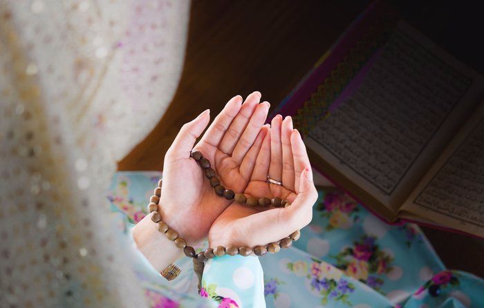 Gambar mushaf al-Quran terbuka dengan latar belakang surah Zikir Fatimah
