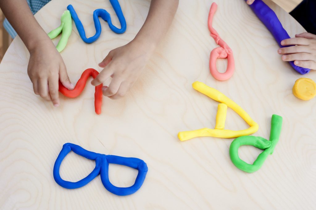 Anak kecil memuat huruf menggunakan play-doh