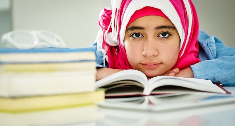 Gadis remaja perempuan sedang duduk merenung jauh.
