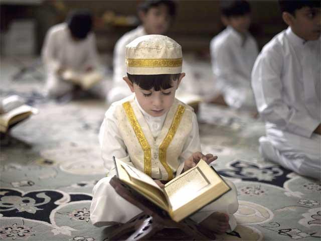 Kanak-kanak lelaki muslim sedang membaca Al-Quran dengan khusyuk