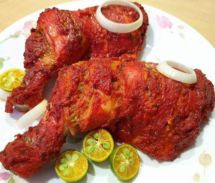 Gambar ayam tandoori berwarna kemerahan yang dipanggang.