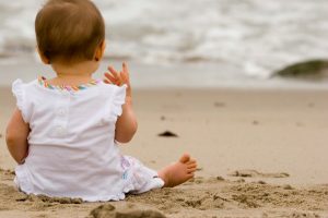Bayi sedang duduk di atas pasir pantai