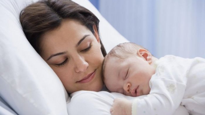 Gambar bayi sedang tidur secara meniarap di atas dada ibunya.
