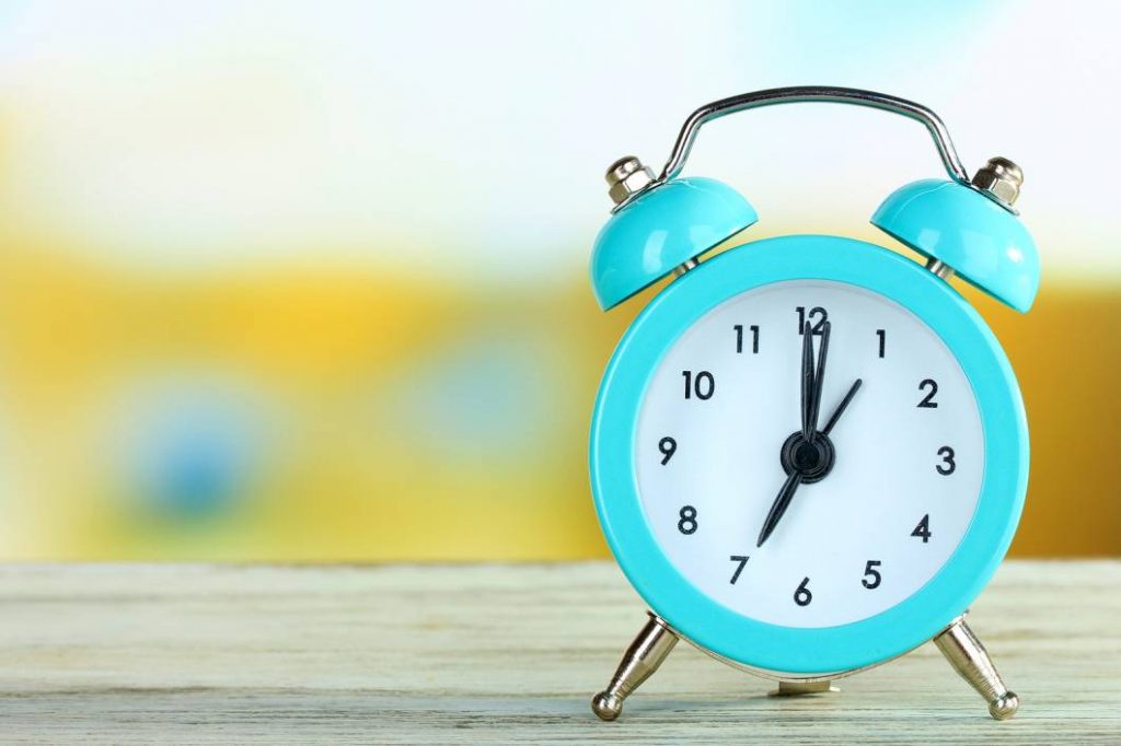 Jam alarm di atas meja yang cerah untuk urus masa