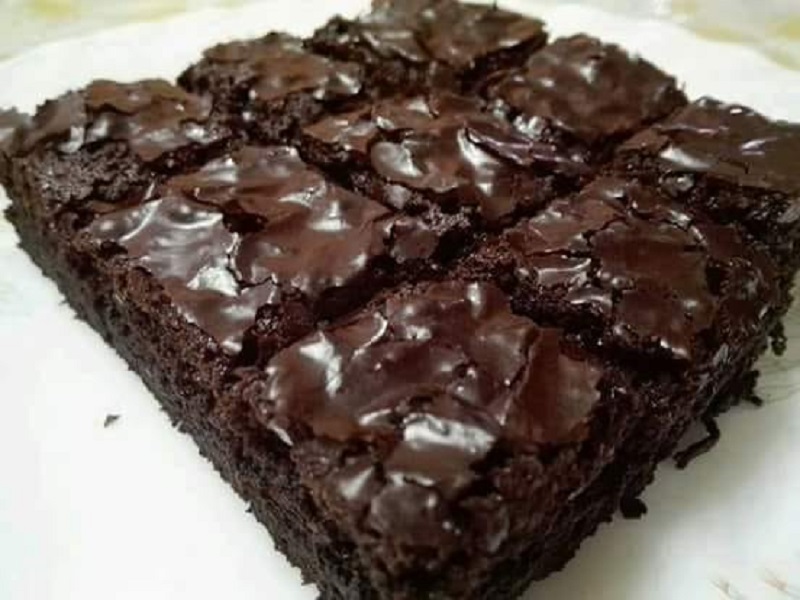 Sekeping brownies berkedut berwarna coklat gelap yang telah dipotong di atas piring.