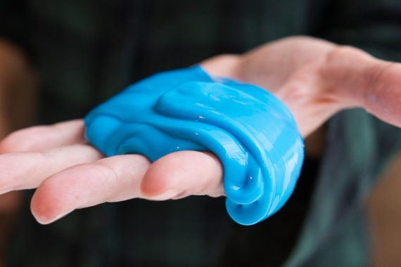 Kanak-kanak sedang bermain slime buatan sendiri yang berwarna-warni di atas meja.