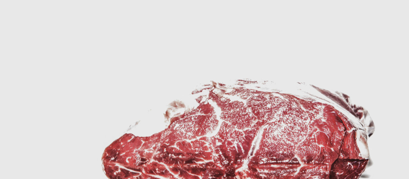 Pelbagai potongan daging lembu mentah yang disusun di atas papan potong kayu untuk dimasak.