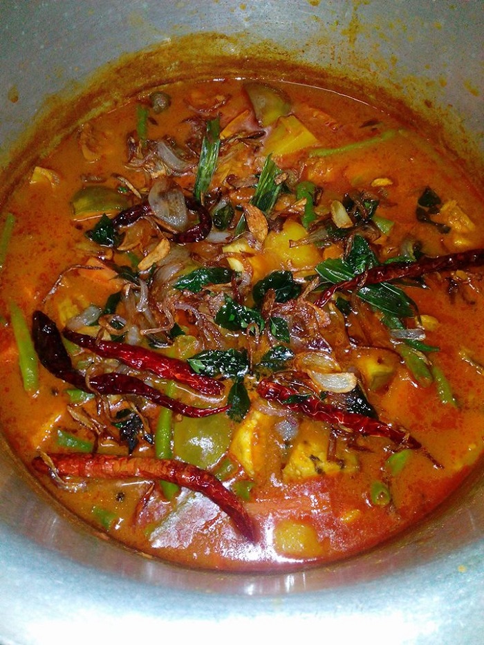 Sebuah mangkuk berisi dalca ayam dengan kuah pekat dan sayur-sayuran.