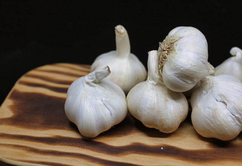 Satu ulas bawang putih putih yang dikupas di atas meja kayu sebagai latar belakang