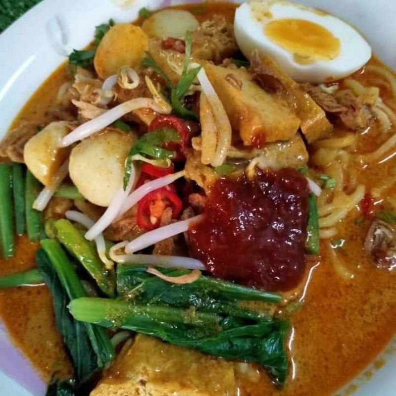 Mangkuk mee kari bersama kuah pekat, tauhu, fishball dan hiasan taugeh serta limau nipis