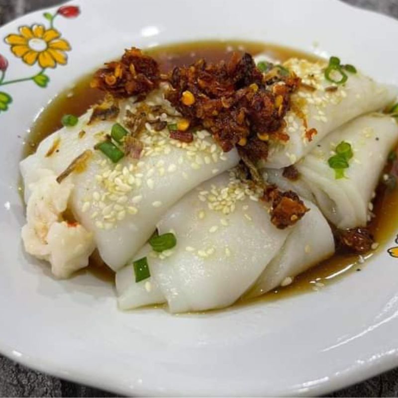 Sekeping chee cheong fun berkuah kicap dengan udang dan taburan bijan serta daun bawang.