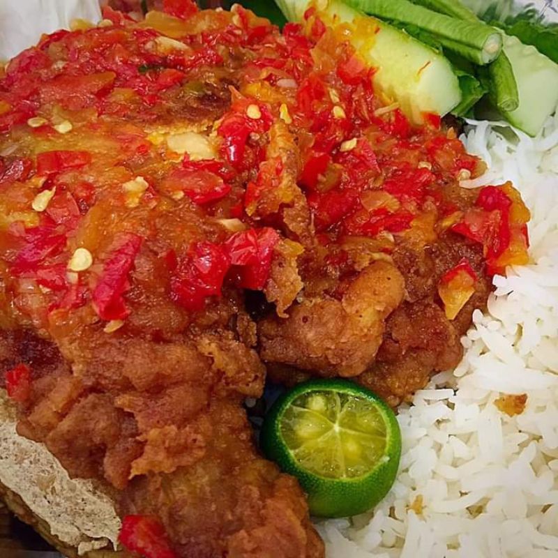 Hidangan nasi ayam geprek dengan ayam goreng tepung dan sambal cili padi di atas pinggan.