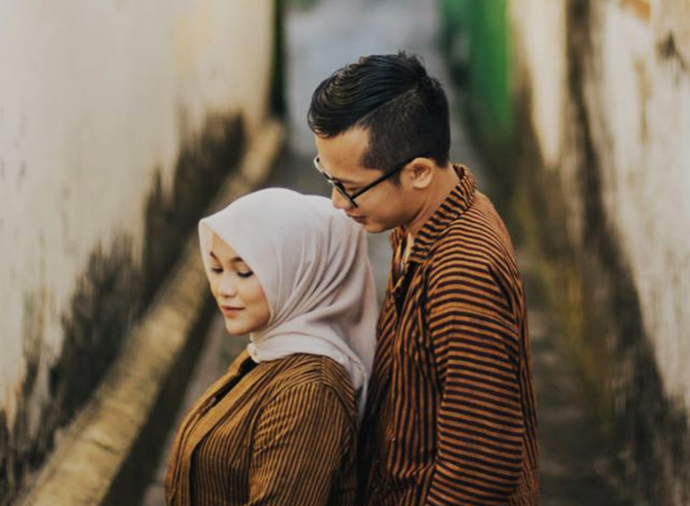 Gambar pasangan pengantin muda tersenyum gembira semasa majlis perkahwinan.