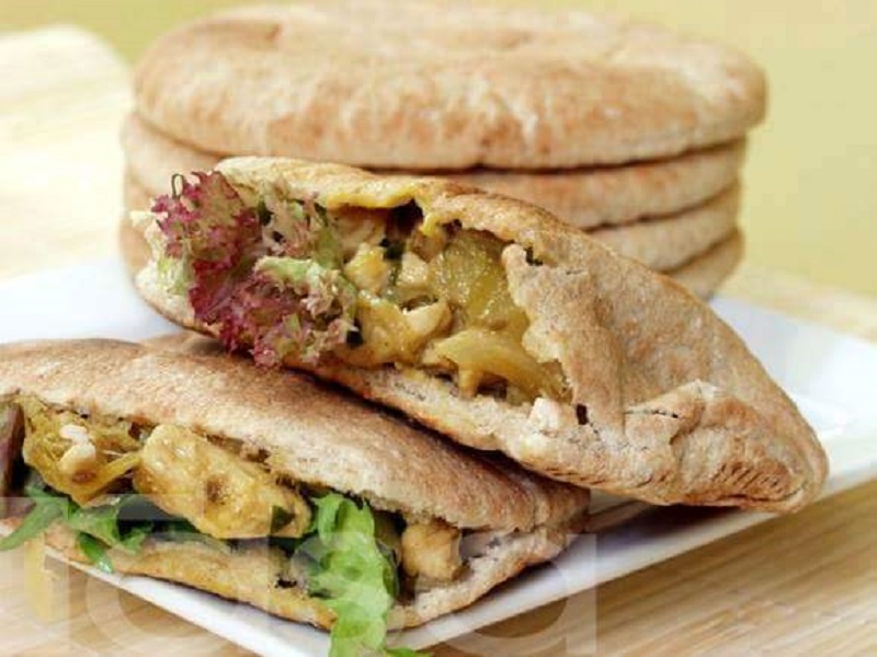 Gambar kebab ayam dalam roti pita dengan inti ayam dan daun salad.