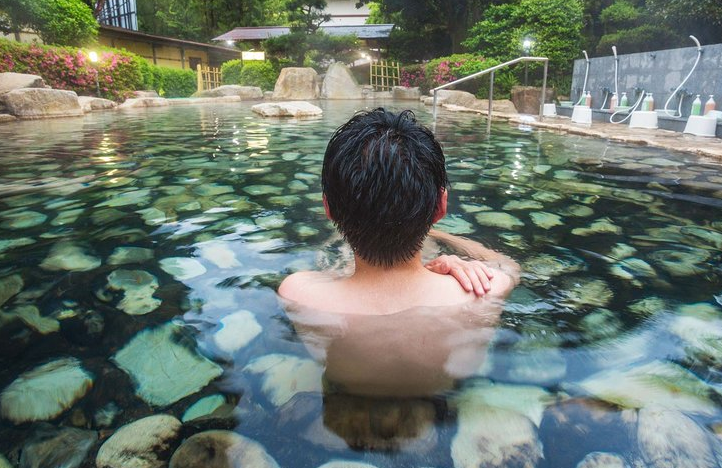Gambar suasana mandi berendam dalam tab mandi air panas yang berkabus untuk merehatkan badan dan mengembalikan tenaga.