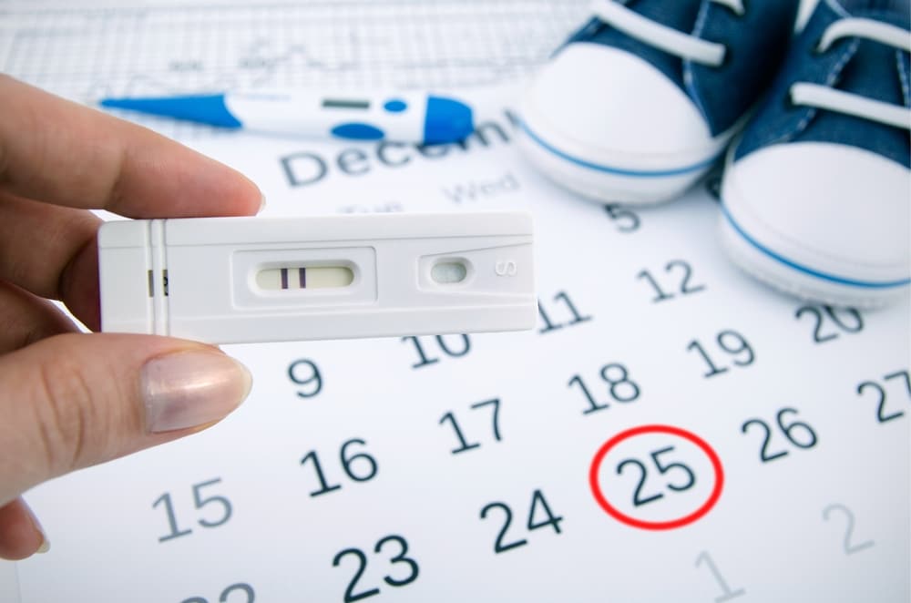 Wanita memegang kalendar dan alat pengesan kesuburan untuk mengira waktu subur