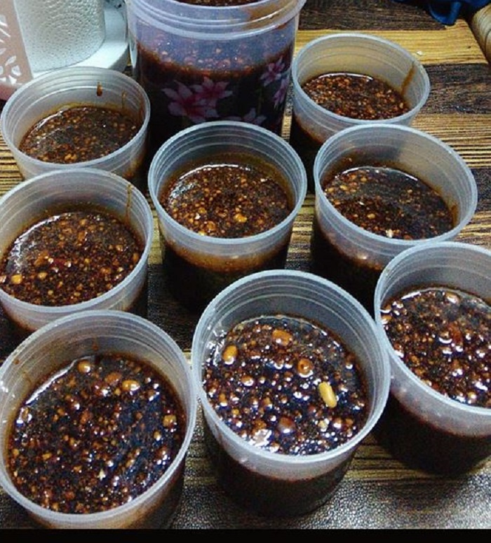 Sebuah mangkuk berisi kuah rojak buah yang berwarna pekat dan gelap.