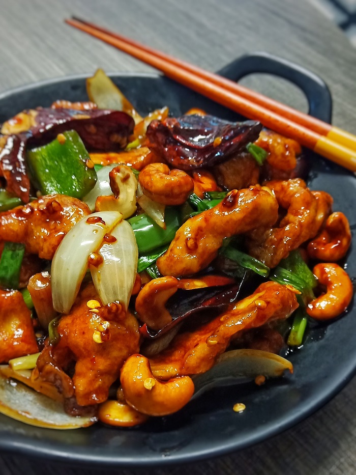 Hidangan ayam kung pao goreng pedas dengan kacang dan sayur-sayuran.