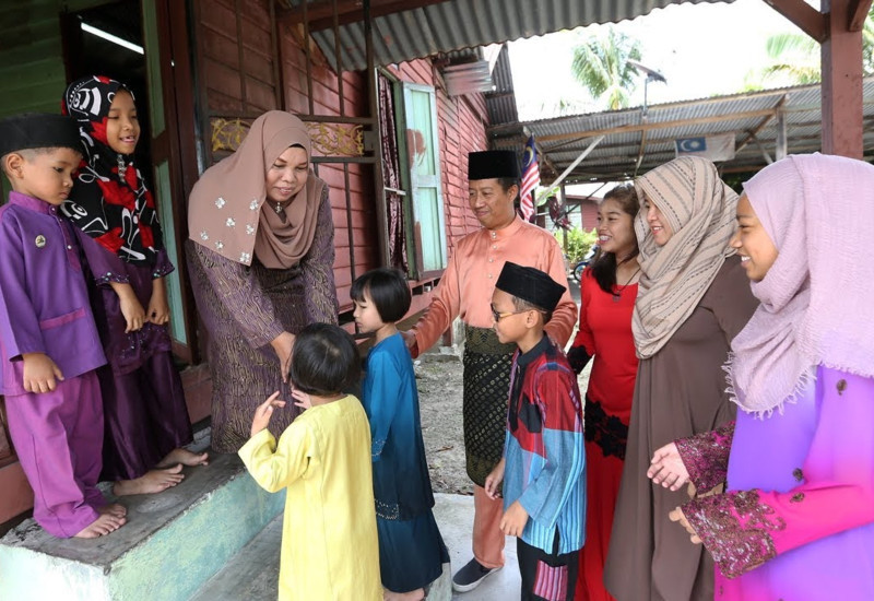 Keluarga berpose di hadapan rumah terbuka