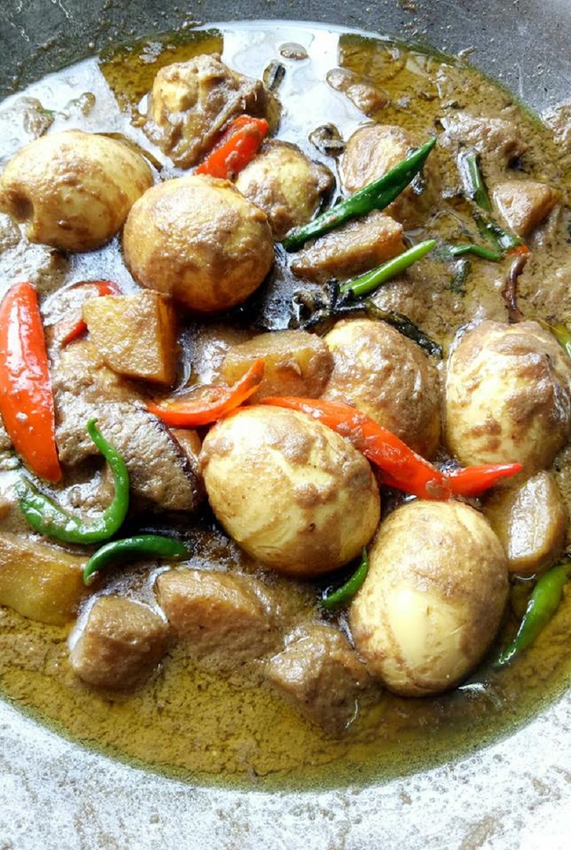 Sebuah hidangan kurma masak telur dengan kuah rempah dan kentang dalam mangkuk.
