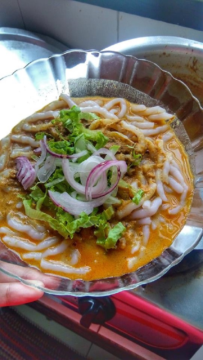 Mangkuk laksa Kedah berkuah kuning pekat dengan mee putih dan ulam-ulaman.