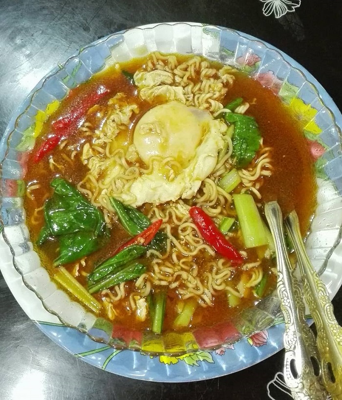 Sepiring maggi bandung yang telah masak dengan kuah, telur dan sayur sawi.