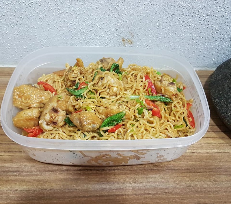 Gambar Maggi Kari Goreng di atas pinggan bersama hiasan daun sup dan cili merah.
