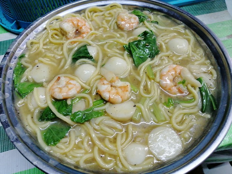 Semangkuk mee kuah dengan udang, sawi dan bebola ikan dalam kuah yang pekat.