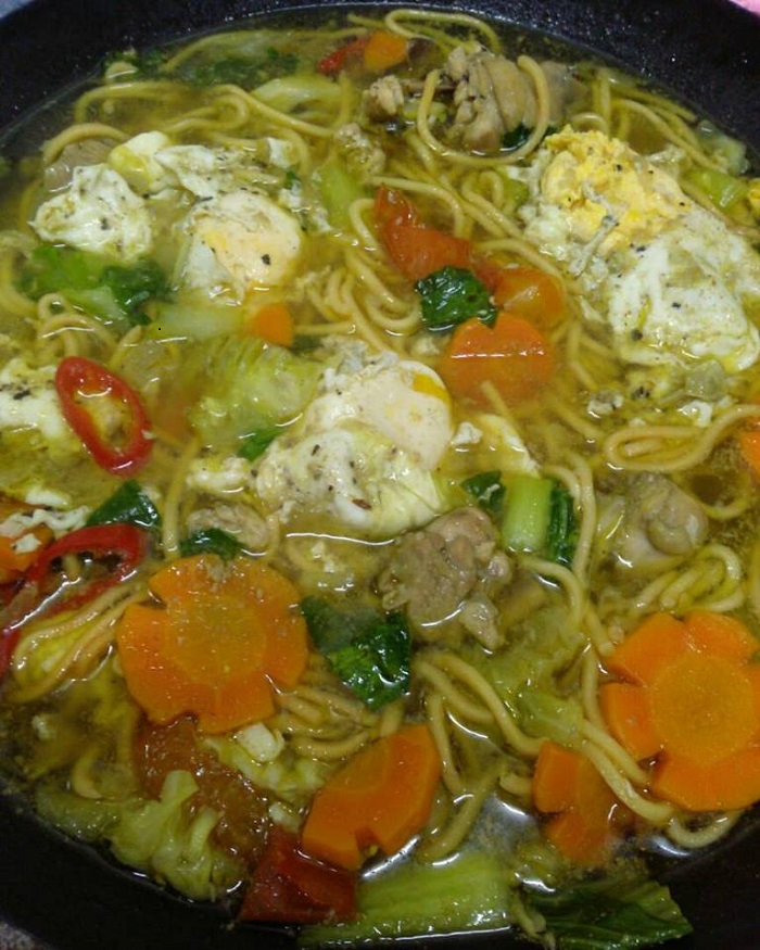 Sebuah mangkuk berisi mee rebus Terengganu dengan kuah, sayur-sayuran dan telur.