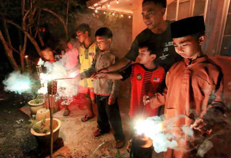 Kanak-kanak menyalakan bunga api di luar rumah