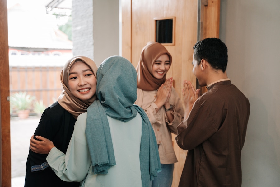 Ilustrasi tetamu berpakaian sopan menghadiri sambutan rumah terbuka semasa hari raya.