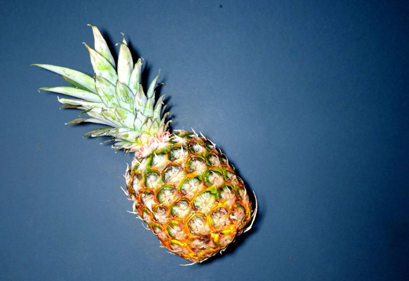 Sebuah buah nanas segar yang telah dipotong di atas meja kayu.