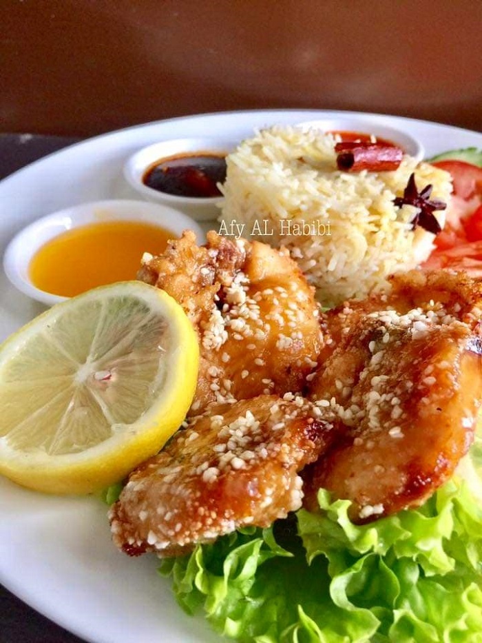Sekeping gambar sos madu lemon yang sedap dituang ke atas ayam goreng crispy untuk hidangan nasi ayam.