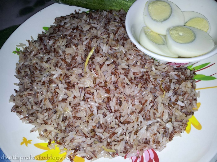 Sepinggan nasi dagang Kelantan berwarna kemerahan dihidangkan bersama gulai ikan tongkol.