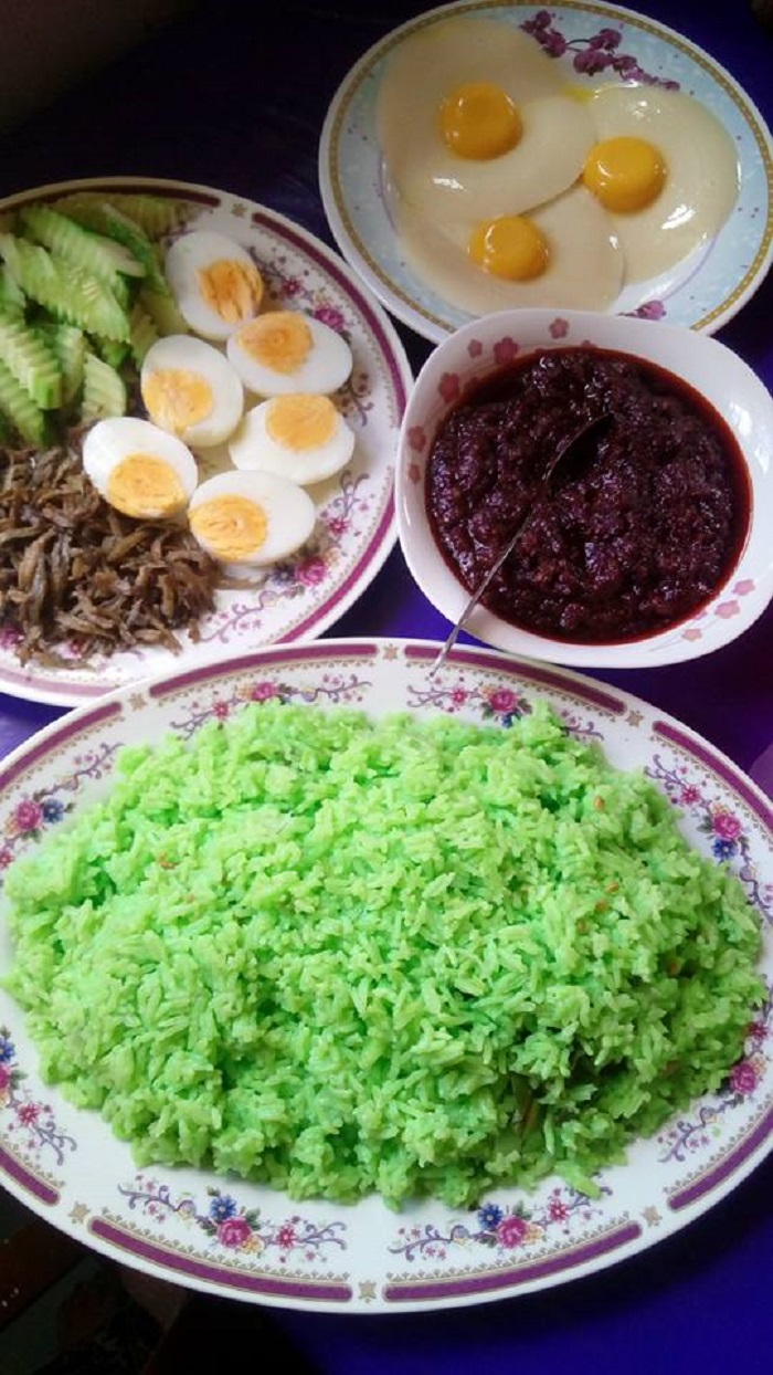 Nasi lemak pandan hijau dihidangkan bersama sambal, telur, ikan bilis dan timun.