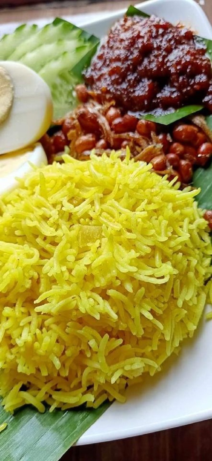 Sepinggan nasi lemak utara berwarna kuning dihidang bersama sambal sotong dan acar timun.