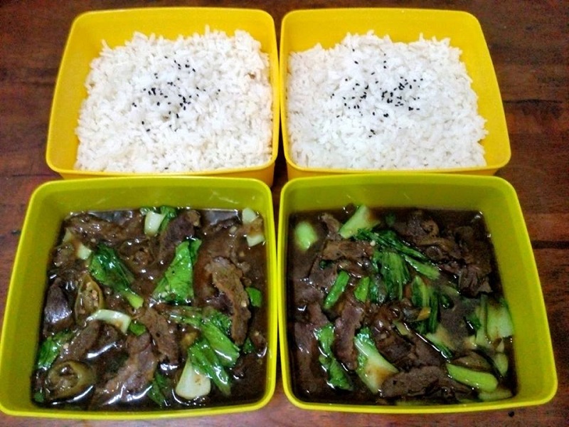 Gambar hidangan nasi putih diasingkan dengan daging goreng blackpepper dan sayur pak choy di dalam bekas plastik.