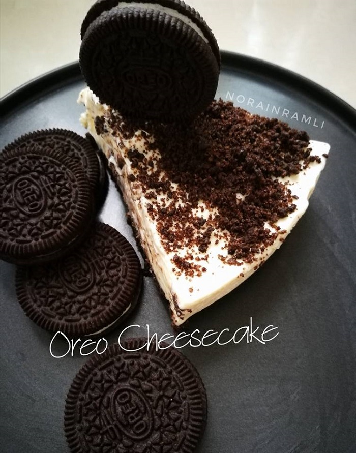 Kek Oreo cheesecake lembut yang dipotong di atas meja, dihias dengan hancuran biskut Oreo.