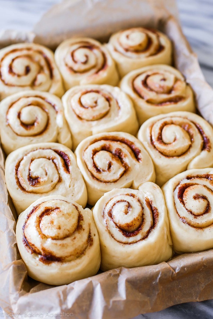 Kepingan cinnamon rolls yang dibakar berwarna keperangan dalam loyang.