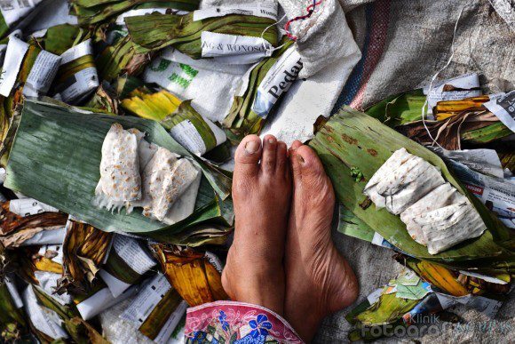 Gambar seorang penjual tempe di pasar sedang memeriksa tempe buatannya.