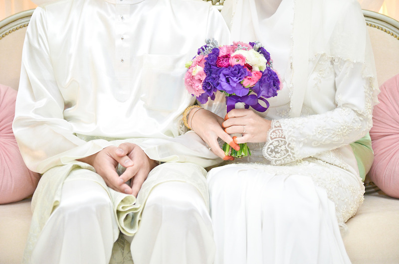 Ilustrasi pasangan pengantin Muslim dalam majlis akad nikah.