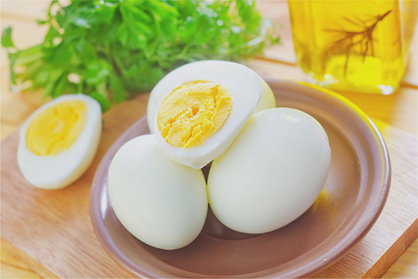 Dua biji telur rebus dipotong di atas piring putih menunjukkan kuning telur yang masak.