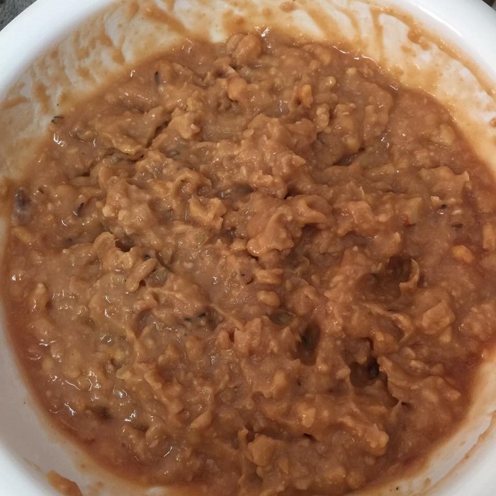 Mangkuk berisi kacang pool daging cincang dihidang bersama hirisan bawang, cili hijau dan telur mata.