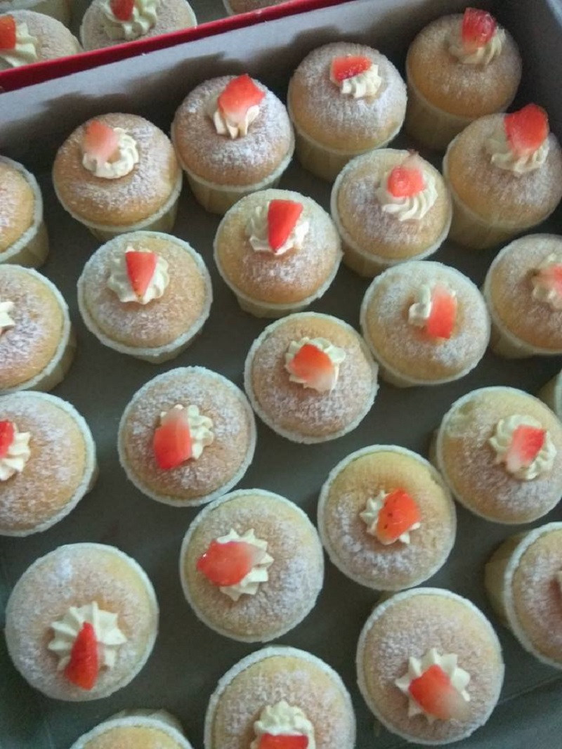 Kek cawan chiffon Hokkaido yang telah siap dihias dengan krim putih di atas cawan kertas.