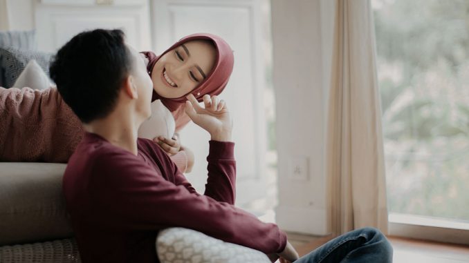 Pasangan suami isteri muslim sedang duduk bersama bergurau senda.
