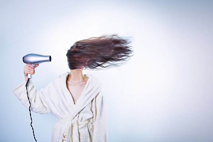 Gambar rambut wanita diasingkan dengan mesin pengering rambut (hair dryer).