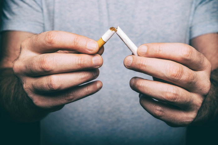 Gambar tangan memegang rokok yang sedang cuba dihentikan tabiatnya secara semula jadi
