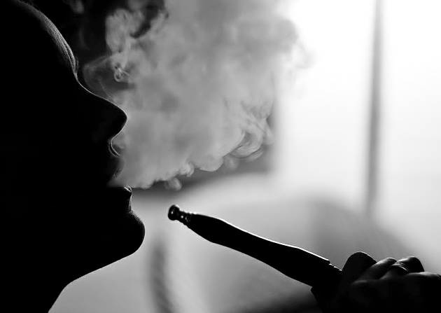 Gambar sebatang paip shisha atau hookah bersama kepulan asap di kafe.